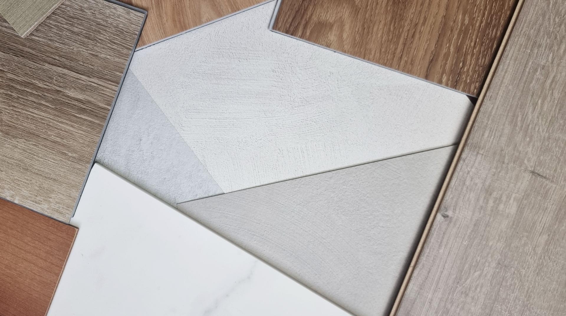 combination of interior material samples mood board contains wooden vinyl tiles, engineering flooring tile, concrete laminated, white marble stone in close up view.